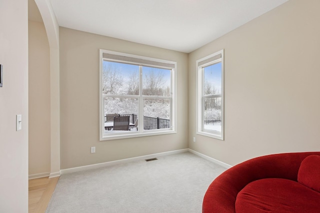 living area with arched walkways, carpet, visible vents, and baseboards