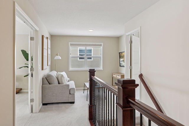 hall with light carpet, baseboards, and an upstairs landing