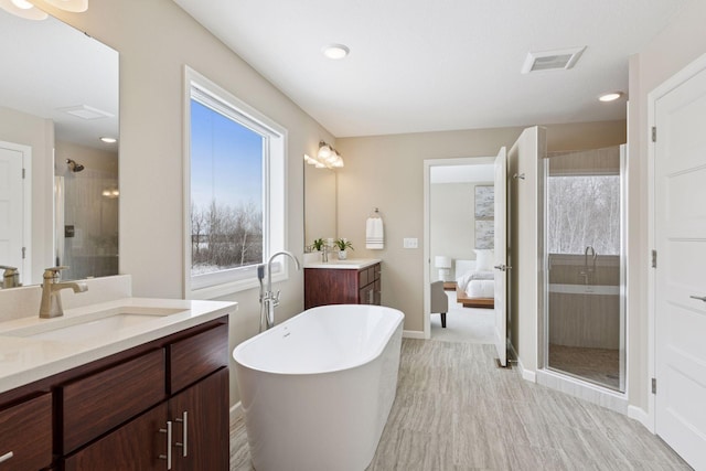 ensuite bathroom with a freestanding tub, visible vents, a sink, and a shower stall