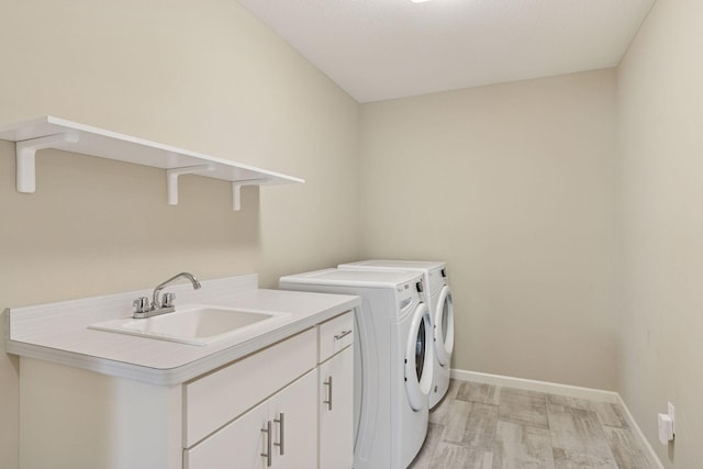 clothes washing area with separate washer and dryer, a sink, baseboards, light wood-style floors, and cabinet space