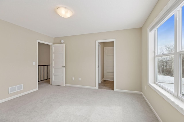 unfurnished bedroom with baseboards, visible vents, and light colored carpet