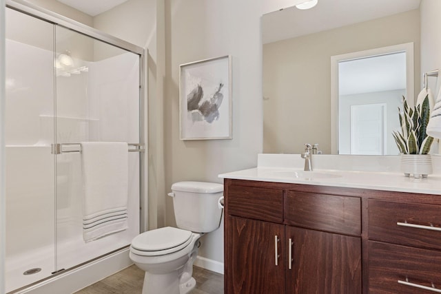 full bathroom with toilet, a shower stall, vanity, wood finished floors, and baseboards