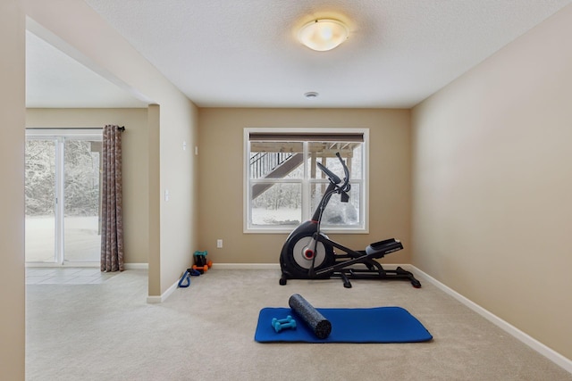 workout area featuring a textured ceiling, carpet, and baseboards