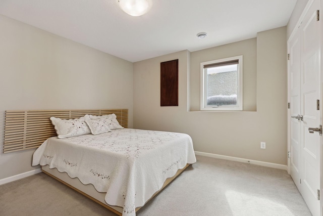 bedroom with light colored carpet and baseboards