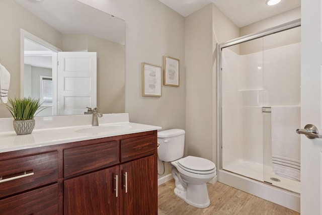 full bath with toilet, a stall shower, wood finished floors, and vanity