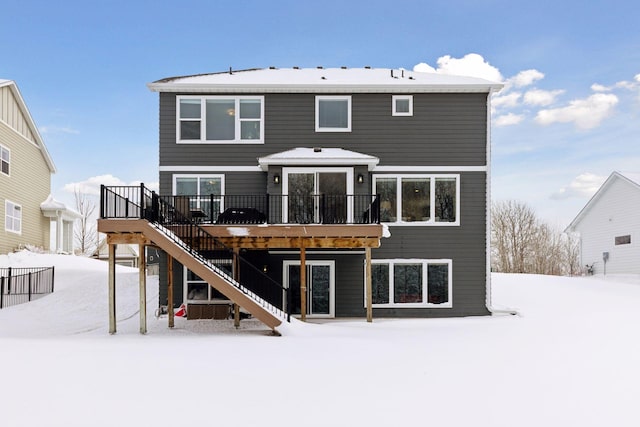 snow covered rear of property with stairway and a wooden deck