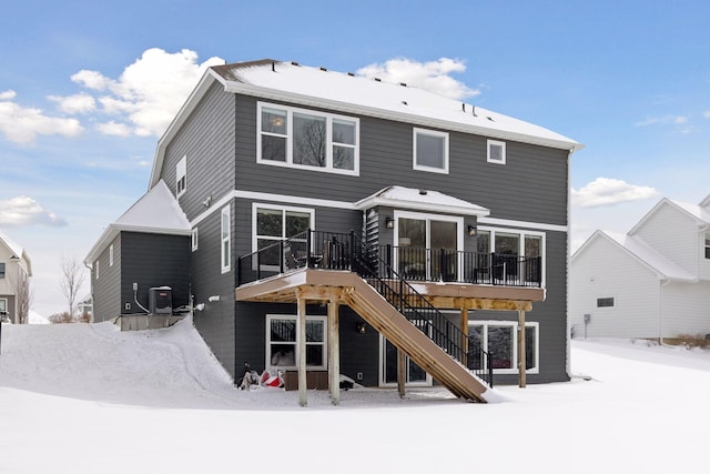 snow covered property with a deck, central AC, and stairway