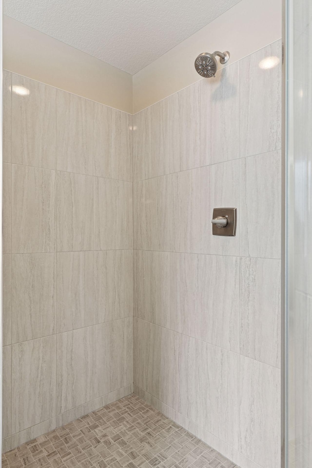 full bath with a textured ceiling and a tile shower