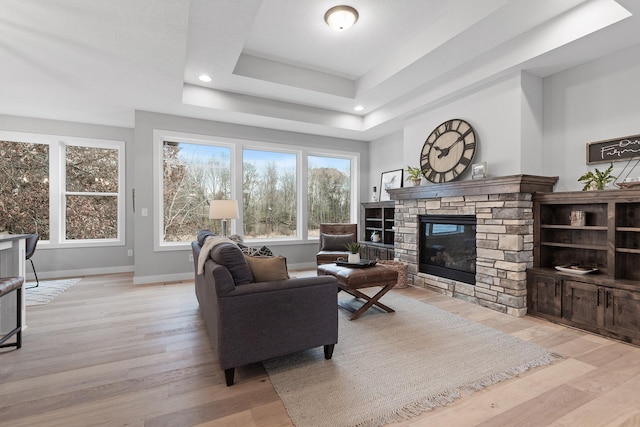 22816 Jarvis St NW, Elk River, MN 55330 - living room featuring a stone fireplace, light hardwood / wood-style floors, and a tray ceiling