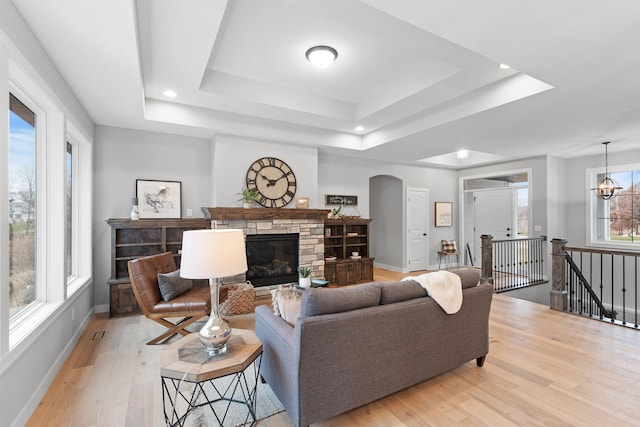 22816 Jarvis St NW, Elk River, MN 55330 - living room with a stone fireplace, light hardwood / wood-style flooring, an inviting chandelier, and a tray ceiling