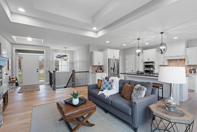 22816 Jarvis St NW, Elk River, MN 55330 - living room featuring an inviting chandelier, a tray ceiling, and light wood-type flooring