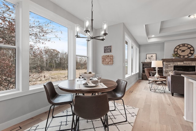 22816 Jarvis St NW, Elk River, MN 55330 - dining room with an inviting chandelier, a fireplace, light hardwood / wood-style flooring, and a raised ceiling