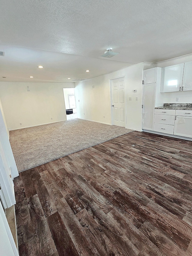 unfurnished living room with a textured ceiling and dark hardwood / wood-style flooring