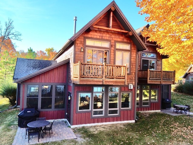 rear view of house with a lawn, a patio, and a balcony