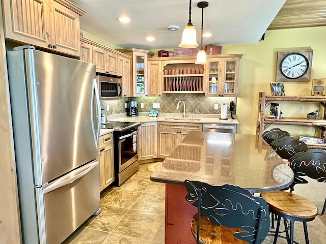 kitchen with sink, appliances with stainless steel finishes, a kitchen island, light brown cabinetry, and decorative light fixtures