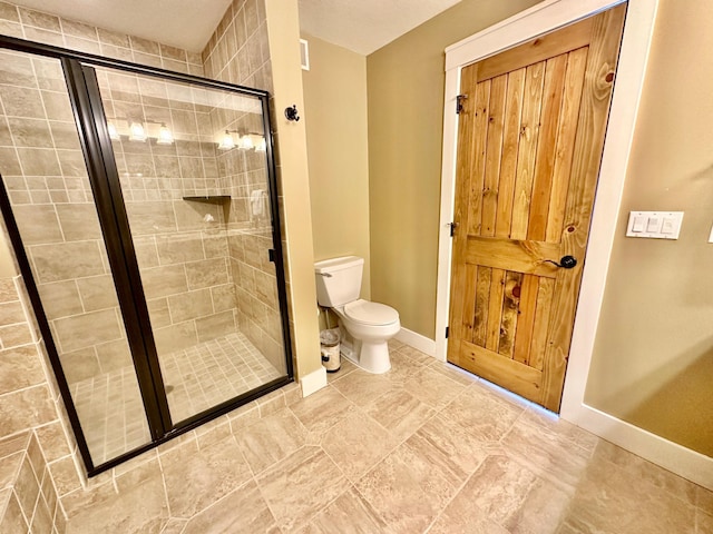 bathroom featuring a shower with door and toilet