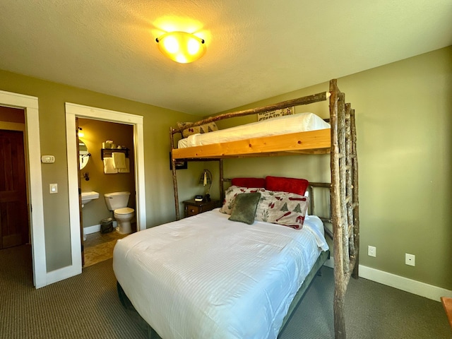 bedroom with connected bathroom, a textured ceiling, and dark carpet