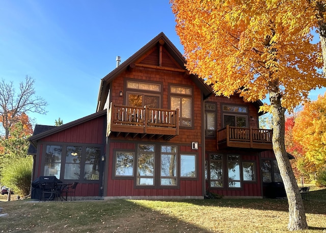 rear view of property featuring a balcony and a lawn