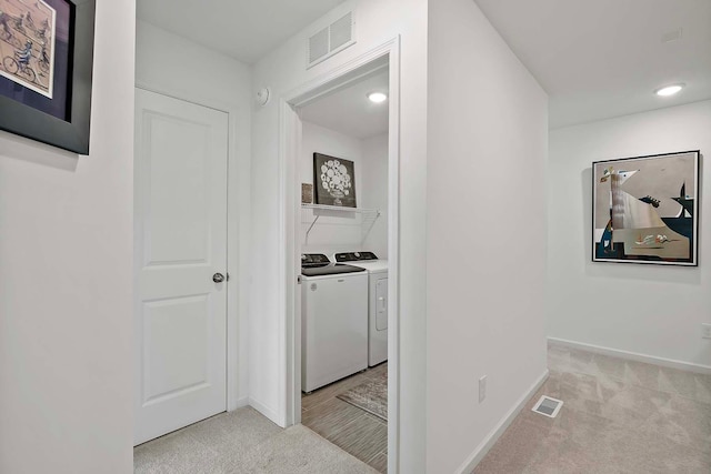 corridor featuring light colored carpet and washing machine and dryer