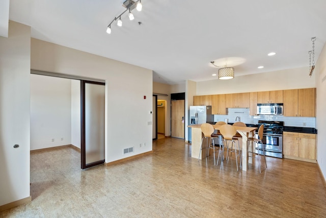 kitchen featuring tasteful backsplash, appliances with stainless steel finishes, and a breakfast bar area