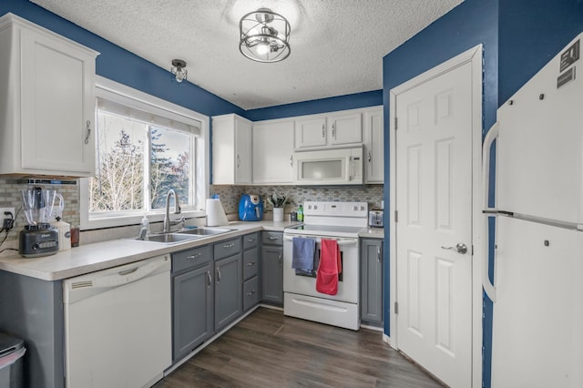 kitchen featuring dark wood-type flooring, a sink, white cabinetry, white appliances, and light countertops