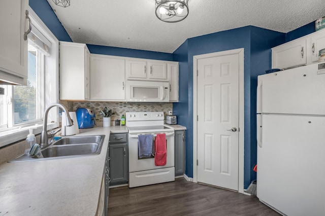 kitchen with backsplash, dark wood finished floors, light countertops, white appliances, and a sink