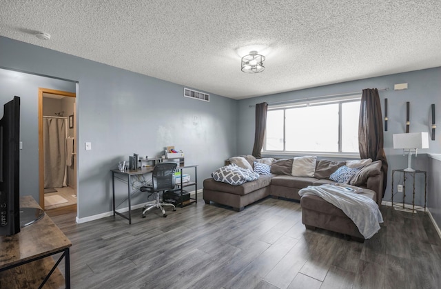 living room with visible vents, baseboards, a textured ceiling, and wood finished floors