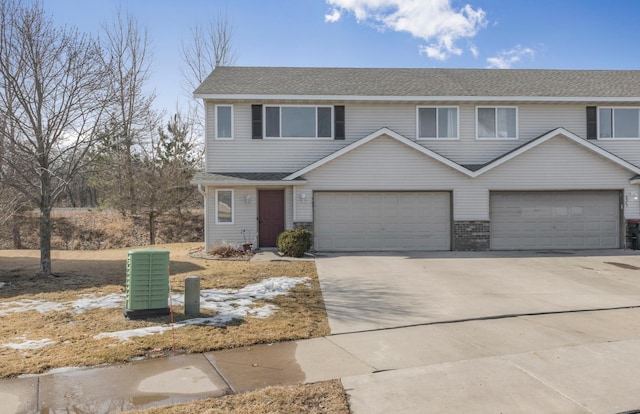 townhome / multi-family property with brick siding, an attached garage, concrete driveway, and a shingled roof