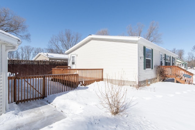 view of snowy exterior featuring fence and a deck