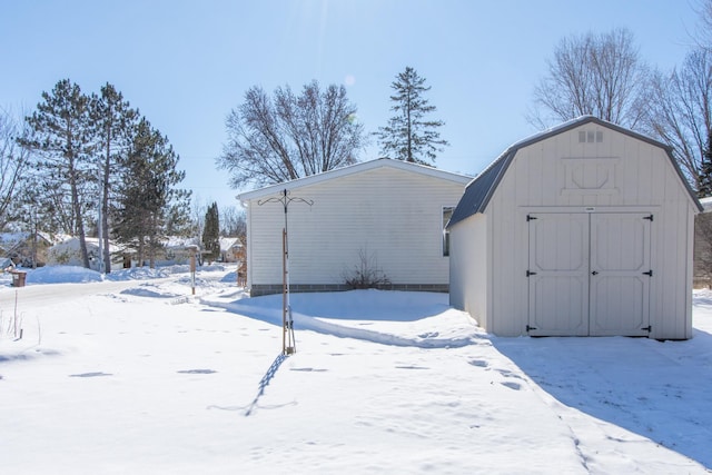 snow covered structure featuring a shed and an outdoor structure