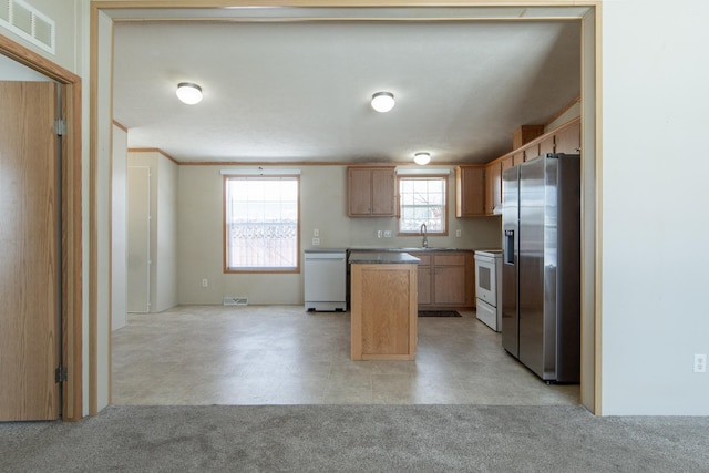 kitchen featuring white appliances, light brown cabinets, visible vents, and a center island