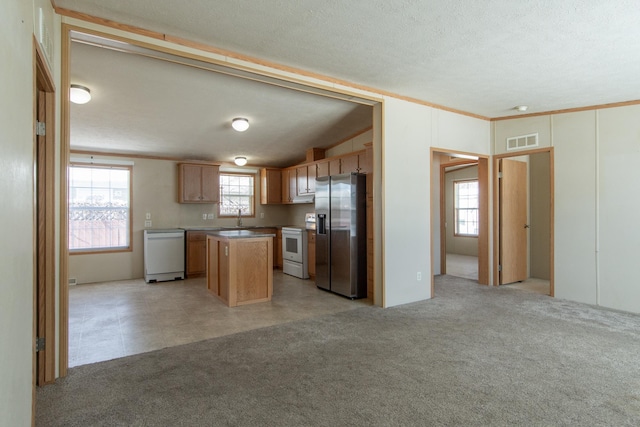 kitchen featuring light carpet, white appliances, visible vents, open floor plan, and a center island