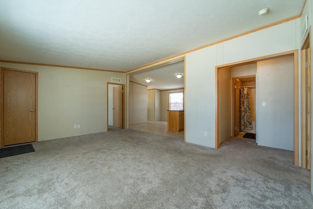 interior space featuring light colored carpet, crown molding, visible vents, and a textured ceiling