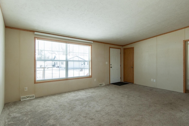 spare room featuring light carpet, visible vents, and a textured ceiling