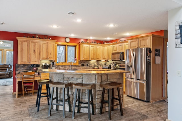 kitchen featuring a breakfast bar area, light hardwood / wood-style flooring, sink, and stainless steel fridge