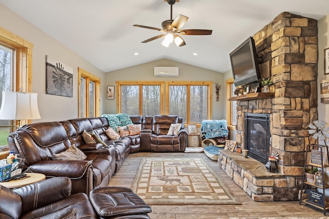 living room featuring vaulted ceiling, light wood-type flooring, ceiling fan, a fireplace, and a wall mounted AC