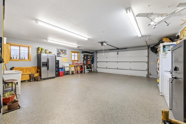 garage with a garage door opener and stainless steel fridge with ice dispenser