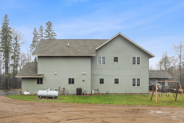 rear view of house with cooling unit and a yard