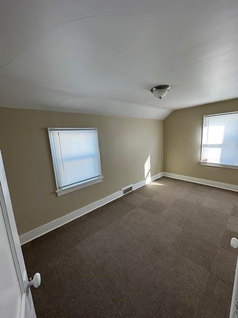 207 7th St SW, Austin, MN 55912 - spare room with baseboards, vaulted ceiling, dark carpet, and visible vents