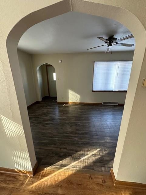 207 7th St SW, Austin, MN 55912 - spare room featuring arched walkways, ceiling fan, baseboards, and wood finished floors