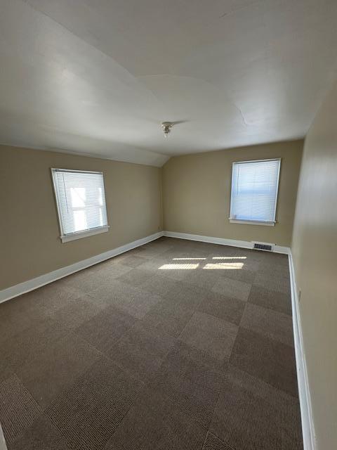 207 7th St SW, Austin, MN 55912 - carpeted spare room featuring visible vents, baseboards, and lofted ceiling