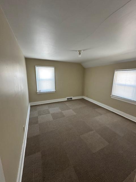 207 7th St SW, Austin, MN 55912 - empty room featuring visible vents, baseboards, dark carpet, and a wealth of natural light