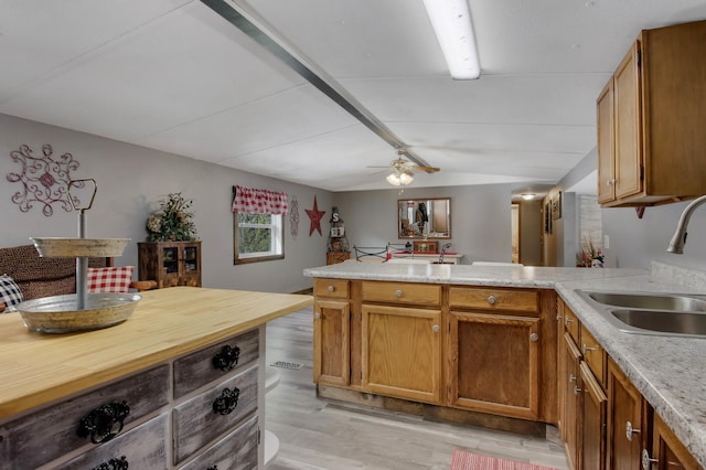 kitchen featuring lofted ceiling, sink, ceiling fan, light hardwood / wood-style floors, and kitchen peninsula