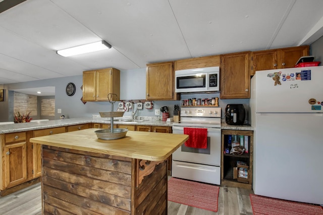 kitchen featuring white appliances, light hardwood / wood-style flooring, butcher block counters, a kitchen island, and kitchen peninsula