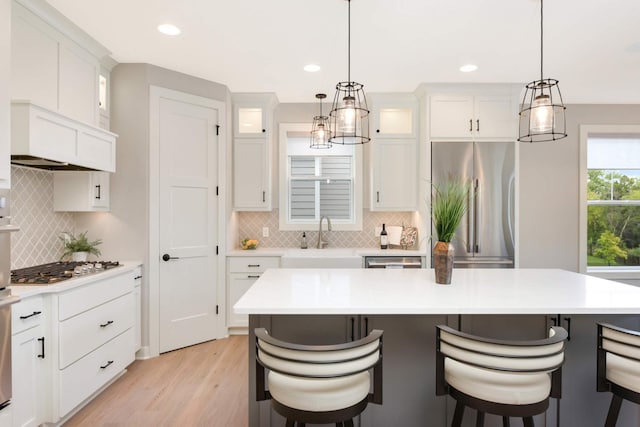 kitchen featuring white cabinetry, a kitchen island, sink, and a kitchen bar