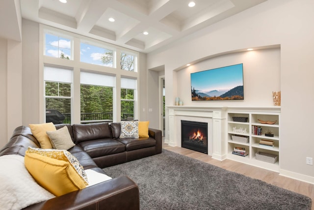 living room with a high ceiling, coffered ceiling, light hardwood / wood-style floors, and beam ceiling