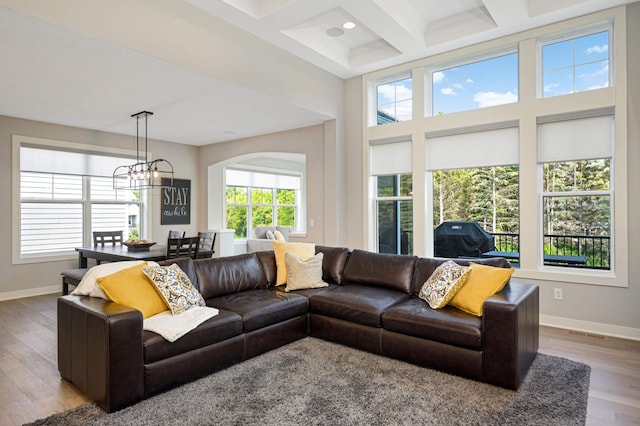 living room featuring coffered ceiling, a chandelier, a towering ceiling, beam ceiling, and hardwood / wood-style floors