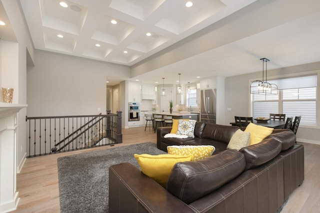 living room with an inviting chandelier, coffered ceiling, light hardwood / wood-style floors, and beamed ceiling