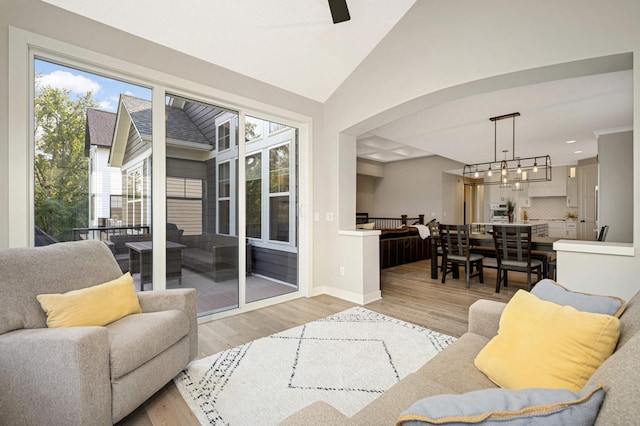 living room featuring an inviting chandelier, lofted ceiling, and light hardwood / wood-style flooring