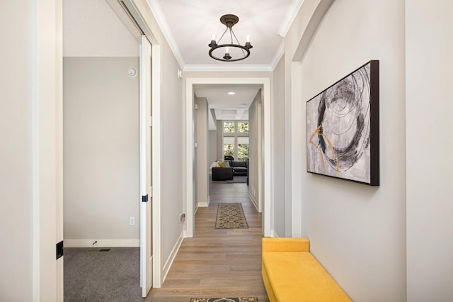 corridor with an inviting chandelier and ornamental molding